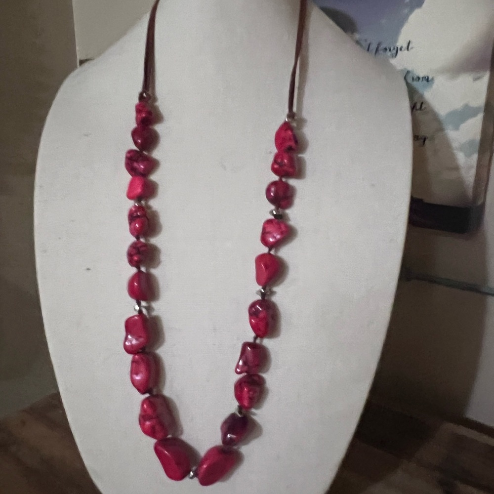 Long, adjustable red stone necklace on a brown cord with silver accents